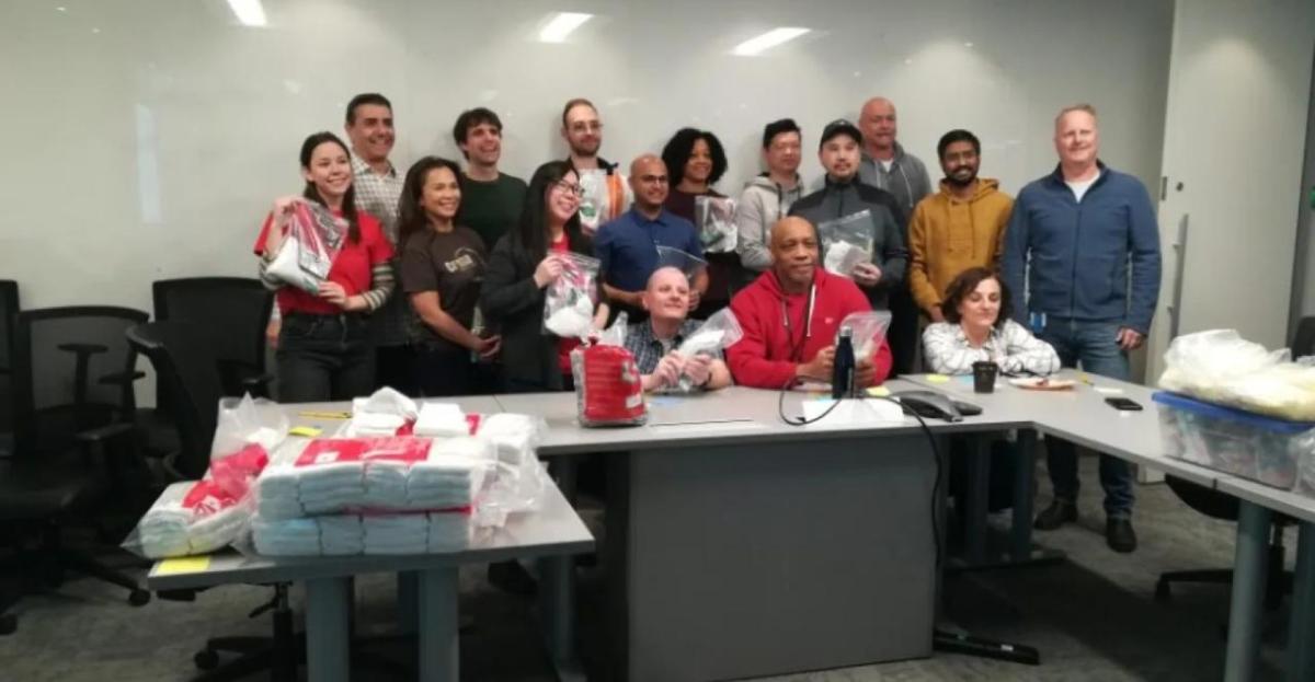 A group posed behind desks, holding bags.