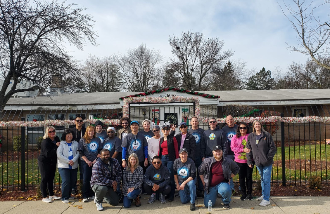 A group of volunteers in front of a fence and building.