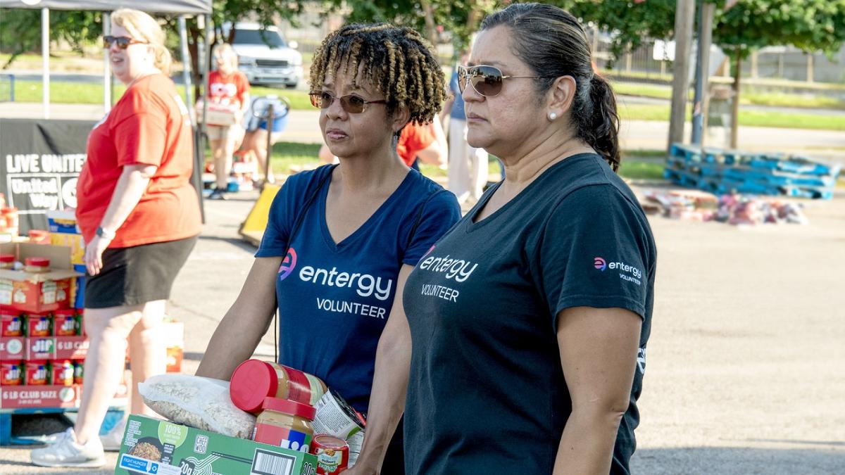 Volunteers outside, one holding a box of food items.