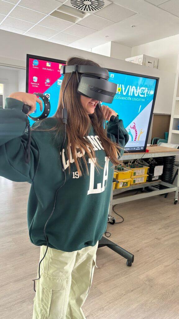 Valeria wearing a VR headset, touching her shoulders. A digital display behind her.