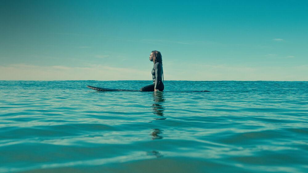 A lone person on a surf board in a large body of water.