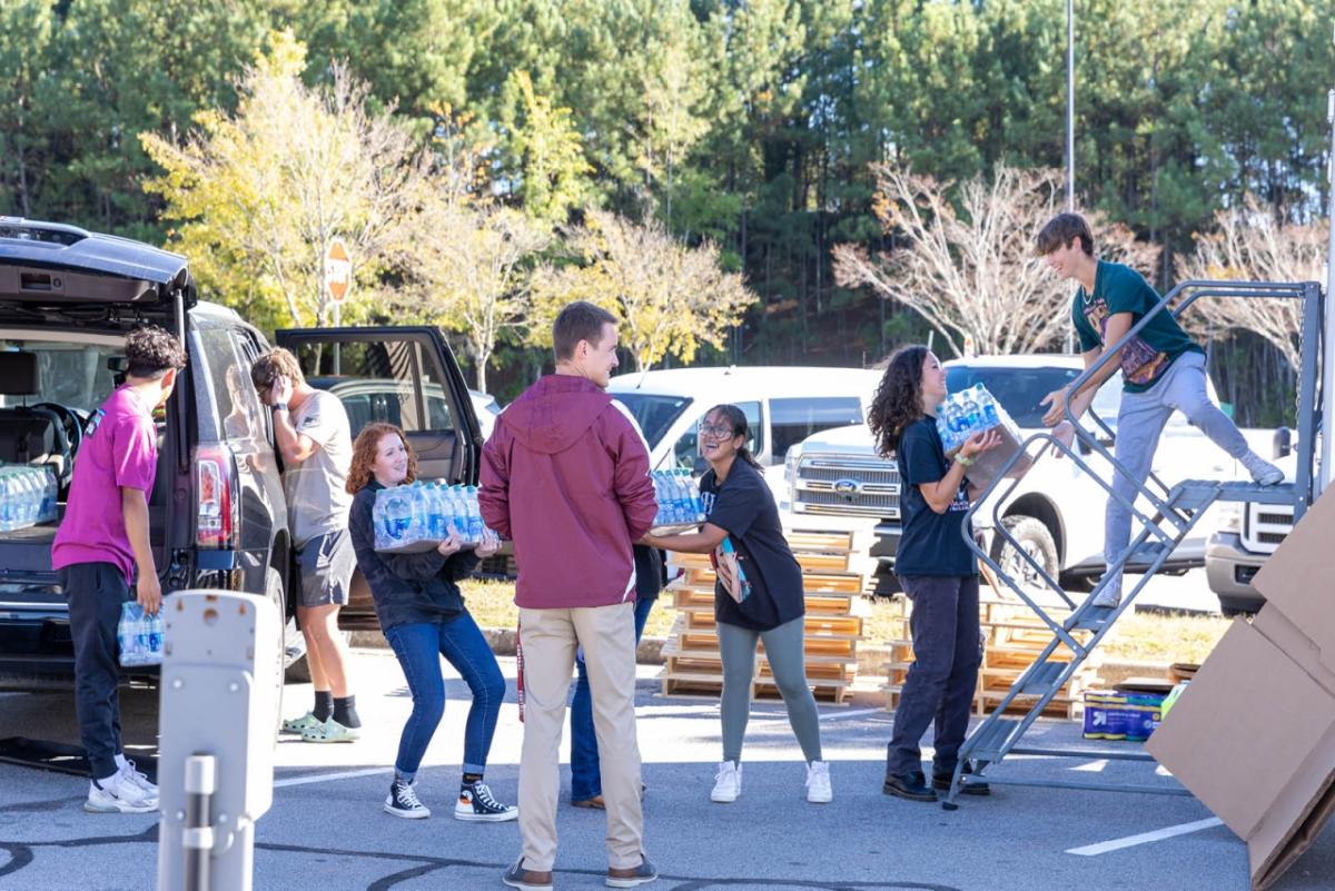 people in a line passing packs of water bottles