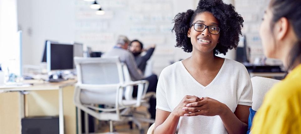 Two people talking in an office setting.