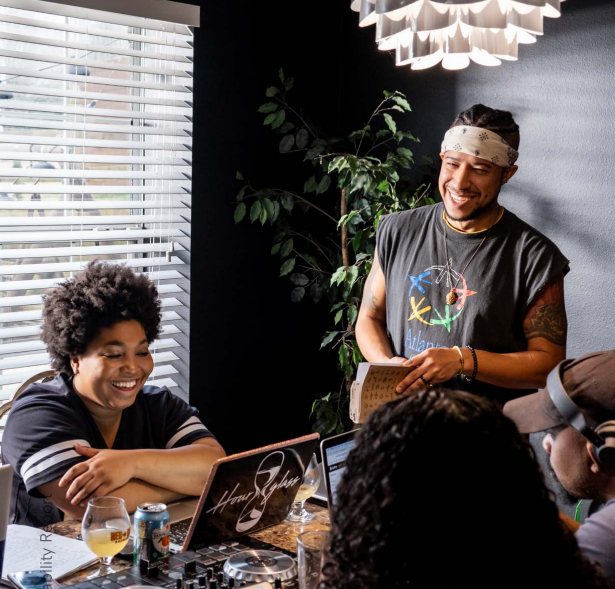 Photo: Werc Crew — XAVIERBLK.COM; people smiling in front of a laptop.