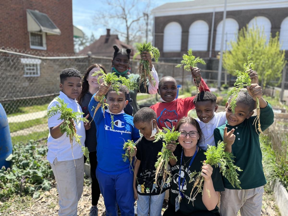 Kids and an adult holding up greens