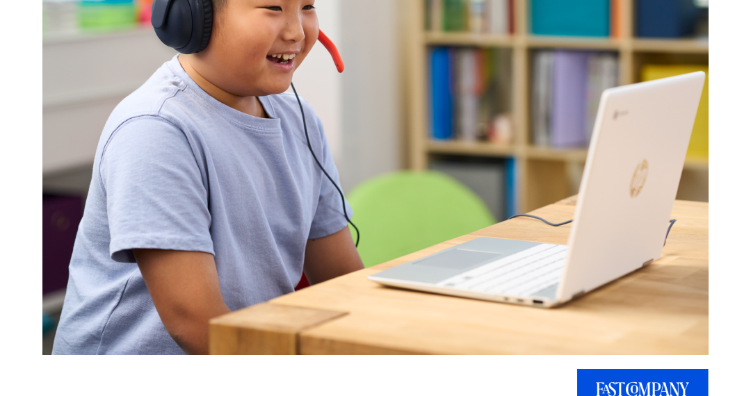 A child with a headset smiling toward a laptop screen