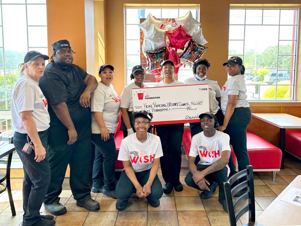 A group of employees posed with a large check