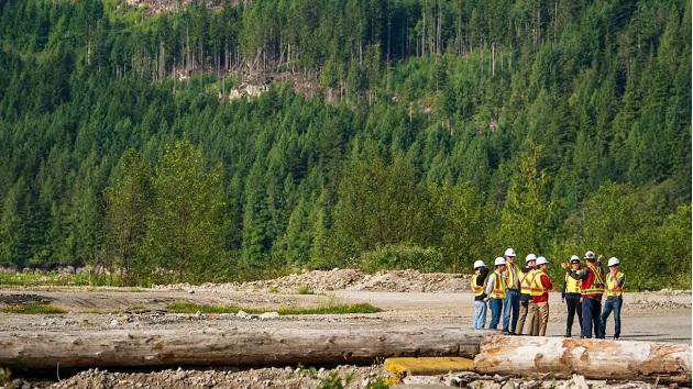 a group of people in safety gear outside, a forest behind them