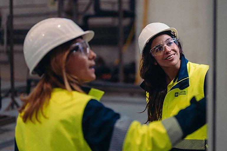 Two people in hard hats looking towards the same thing.