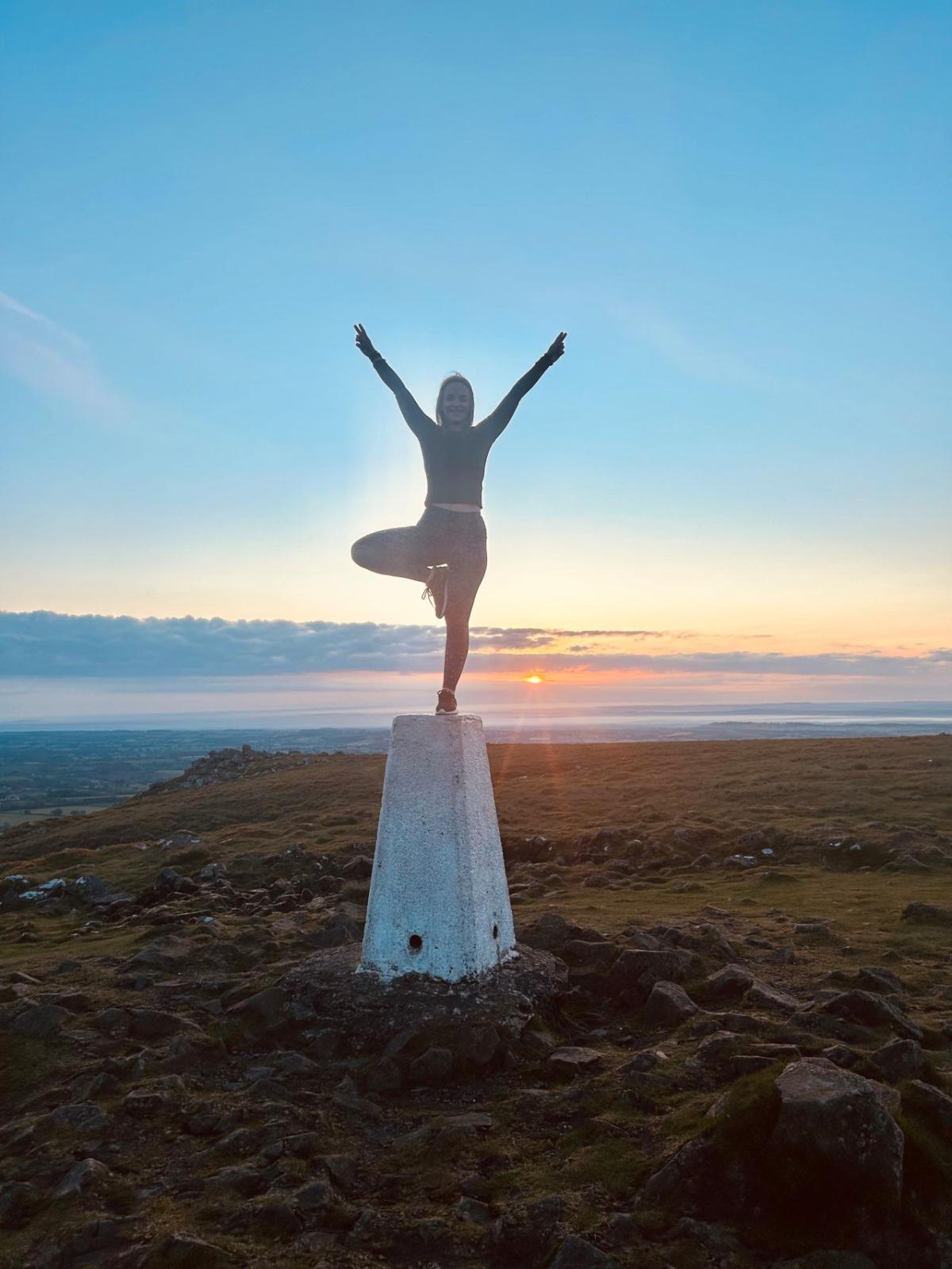 A person doing a pose on top of a small pillar in an open area.