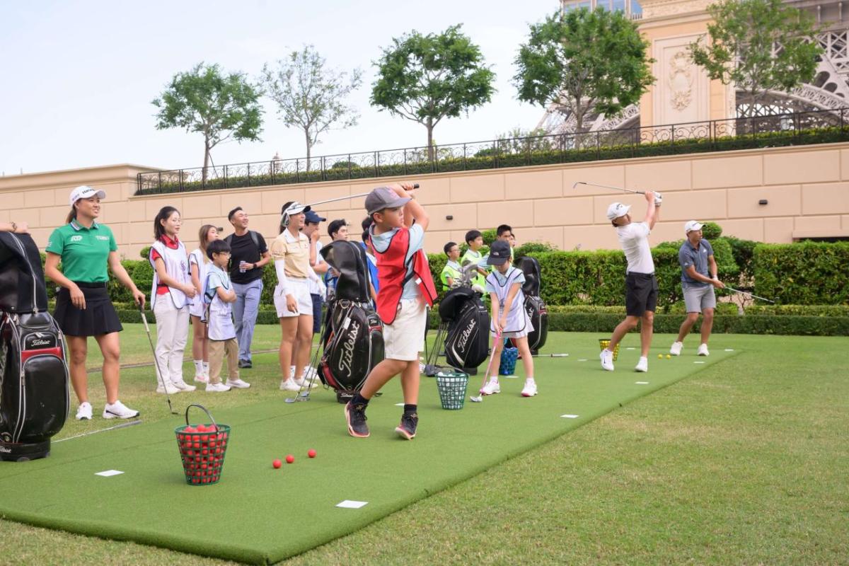 A group of children and adults at a driving range.