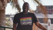 Joe Hawkins standing outside wearing a "Oakland LGBTQ community center" tshirt.