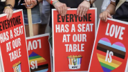 People holding signs that read "everyone has a seat at our table"