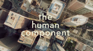 "the human component" over an aerial view of tall city buildings.