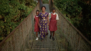 Woman walking across a bridge with her two young daughters