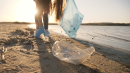 A person picking up plastic waste on a beach